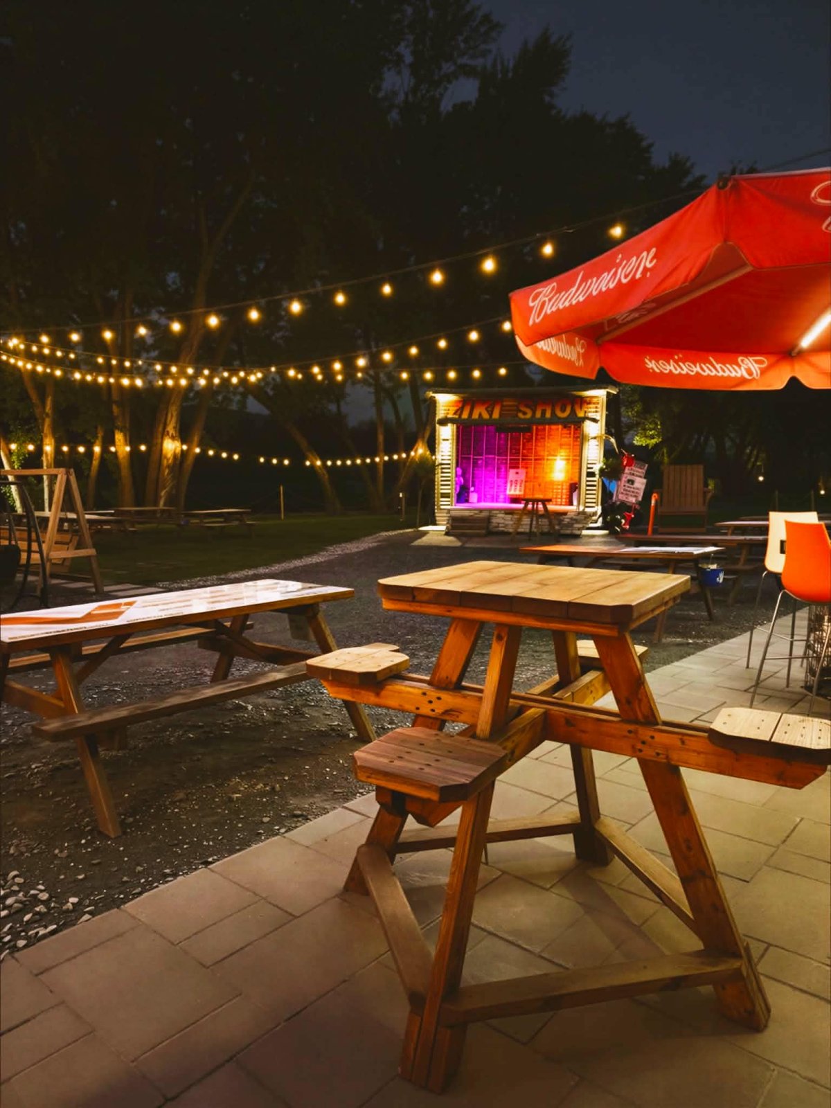 Tables et guirlandes lumineuses devant la scène du Tiki en soirée