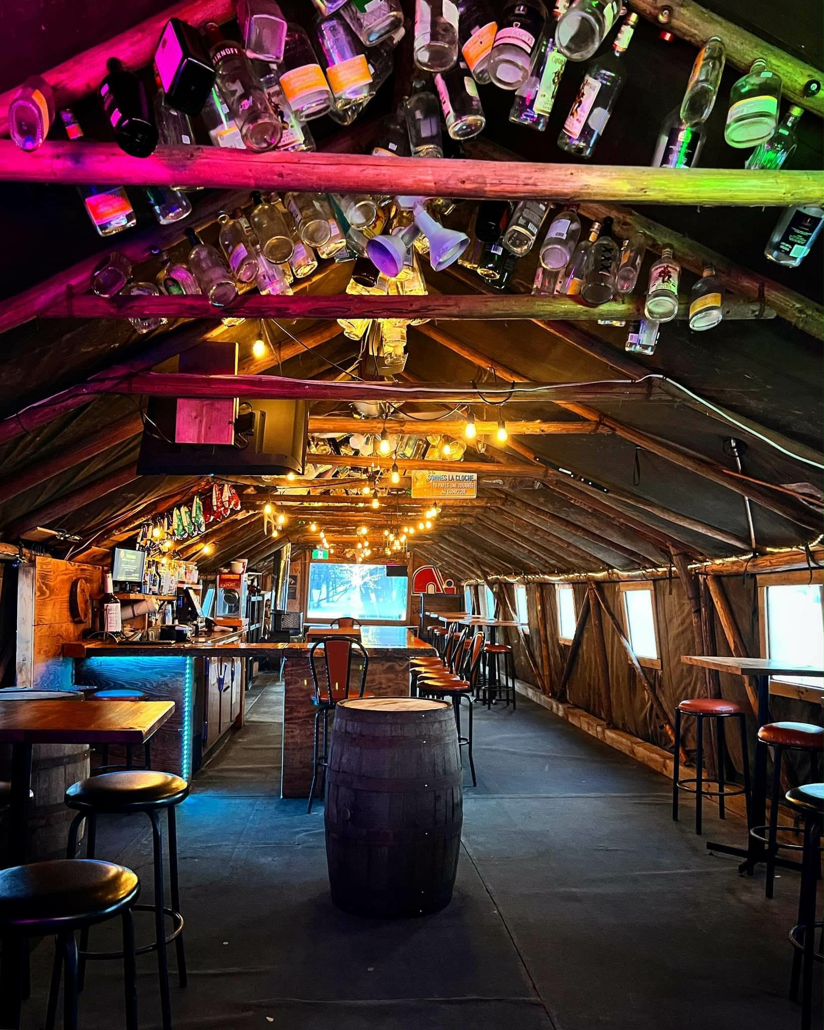 Intérieur chaleureux du Tiki Bar avec son plafond décoré de bouteilles